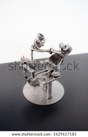 A metal figurine of a dentist and a patient sitting in an armchair.