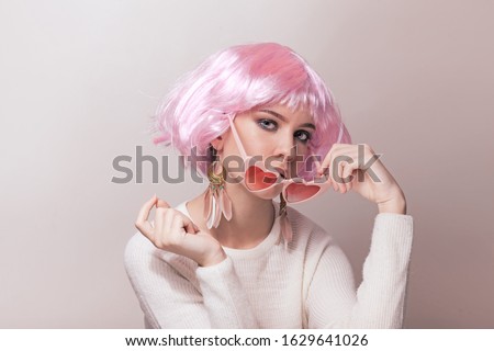 Portrait of teenage model with pink hair posing against pastel background. Studio photo of funky teenager wearing color wig and trendy glasses.