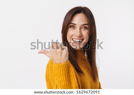 Image of beautiful brunette adult woman wearing sweater smiling and pointing finger aside at copyspace isolated over white background