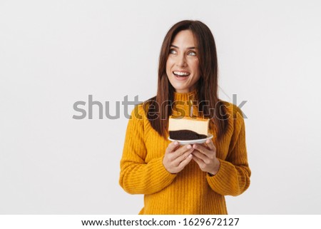 Image of beautiful brunette adult woman wearing sweater smiling and holding birthday cake isolated over white background