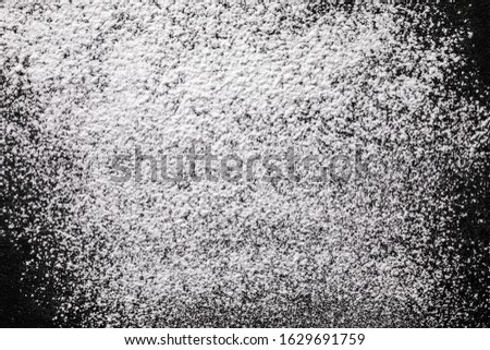 Powdered sugar scattered on a black stone countertop.