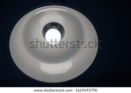 
a bright white lamp shines on the ceiling in a dark room