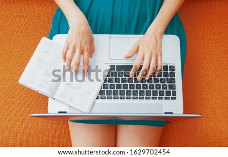 Top view of young woman sitting on sofa with laptop