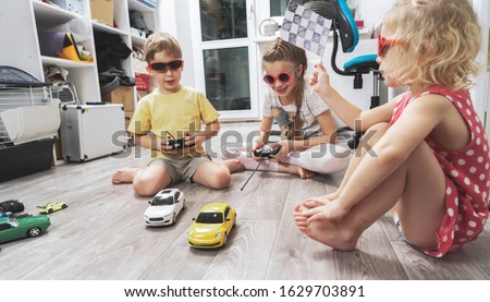 Children's hobbies: Children play at home with radio-controlled models of cars and organized racing competitions. Royalty-Free Stock Photo #1629703891