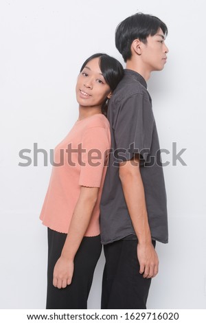  fashion young couple: man and woman standing back to back posing isolated on white background


