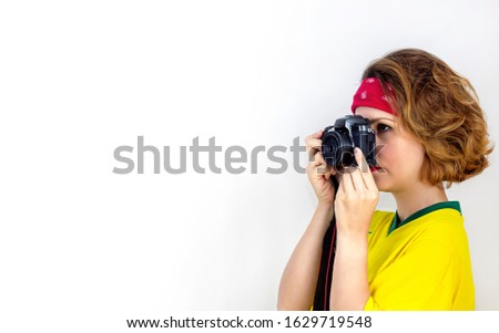 A young woman is holding a modern, digital camera. A girl photographer takes pictures on an isolated background. Copy space