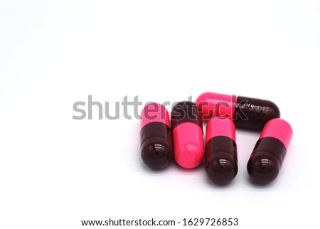 Pile of scattered capsules on white blackground .