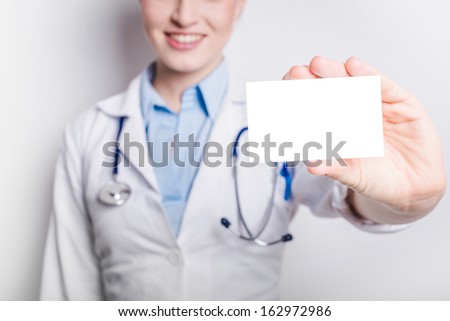 Medical doctor showing business card sign, blank with copy space for text or design. Woman medical professional isolated on white background