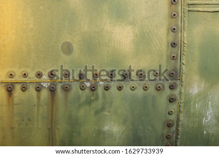 Details of the fuselage of an old aircraft. Old camouflage surface with exfoliated paint and rivets on a military aircraft. Royalty-Free Stock Photo #1629733939