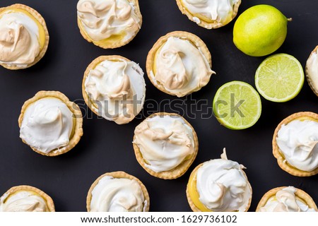 Lemon meringue tartlets made with lime isolated on black surface - overhead photo