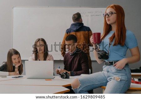Little woman with red hair and glasses drinks coffee on break