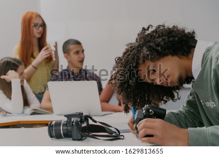 Young african man using camera, writing serial number,number of photo and testing new device