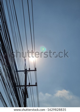 silhouette electric wires with blue sky and sun flare