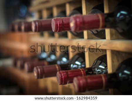 Red wine bottles stacked on wooden racks Royalty-Free Stock Photo #162984359