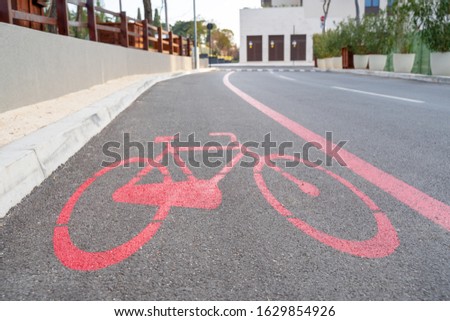 Bicycle lane with special sign made with red paint on the pavement, city view, outdoors, copy space.