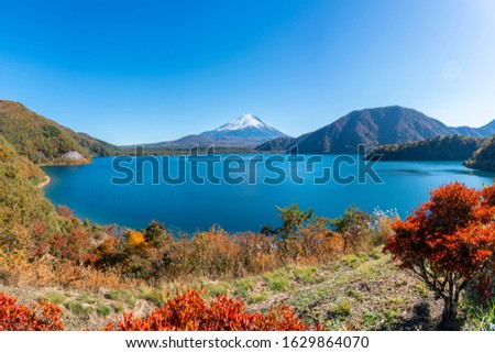 this is a panorama scene from Lake Motosu,Yamanashi,Japan.Lake Motosu (Motosuko) is one of Fuji Five Lakes. Tourist can see Mt.Fuji from this lake.It is blurred red maple leaf in foreground. Royalty-Free Stock Photo #1629864070