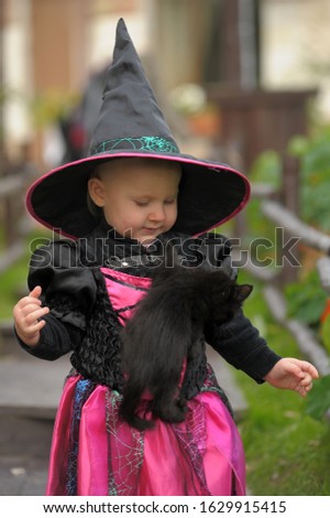 little girl in a witch costume with a black kitten
