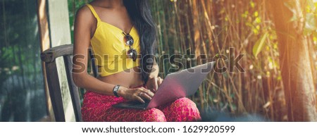 working woman yellow suit pink trousers with Sunglass use computer laptop sitting on wooden chair front home office. internet of things wireless network people communication banner concept. 