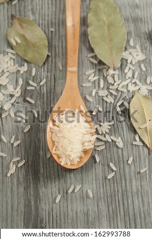 Rice in a wooden spoon and bay leaves