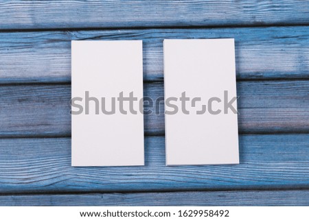 Close-up of mock up two empty stacks of business cards on a blue-violet natural wooden background.