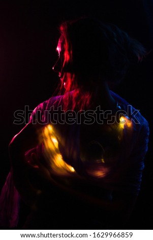 Young redhead Caucasian woman holding fairy lights portrait red background light
