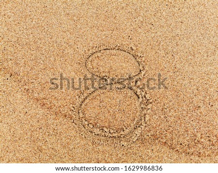 The inscription of handwritten number 8 on wet beach sand. 