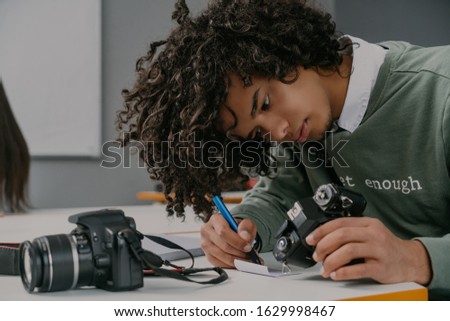 Young muslim african man using camera, writing serial number,number of photo and testing new device