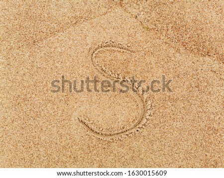 Alphabet S letters handwritten in sand on beach. 