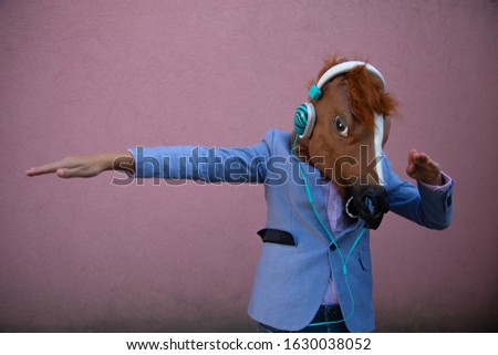 Kid with horse head mask  doing dab and headphones on Royalty-Free Stock Photo #1630038052