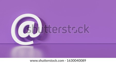 Email Icon or at sign leaning against a purple wall as a communication concept, copyspace for your individual text. 