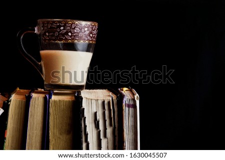 Coffee with milk next to books close-up. Books with a cup of hot aromatic coffee.