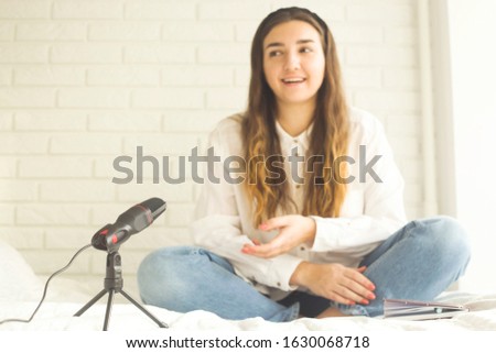 Girl records a podcast with a microphone at home. Modern technologies for creating content for bloggers and influencers.