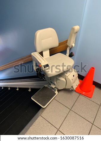 Electric stair chair lift at top of flight of stairs with pylon Royalty-Free Stock Photo #1630087516