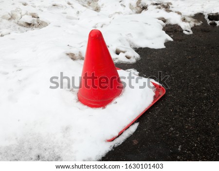 Traffic cone in the snow on the road. Winter season. 