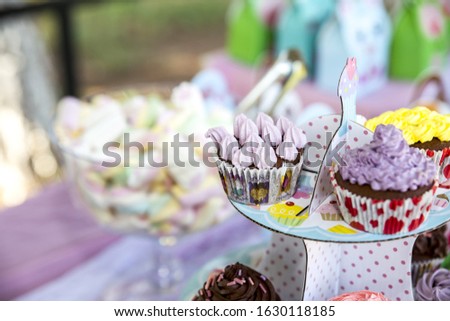 A closeup of cupcakes with colorful toppings on a tray under the lights