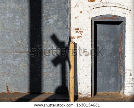 Garage door and door with shadow of a railroad crossing sign on an old abandoned industrial building