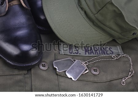 U.S. MARINES Branch Tape with dog tags and boots on olive green uniform background Royalty-Free Stock Photo #1630141729