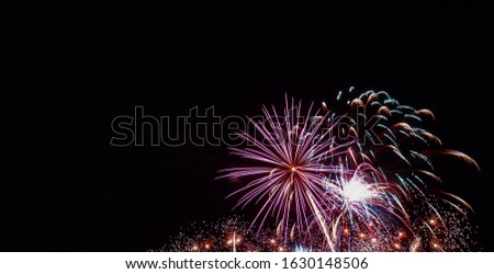 White starburst firework with multiple small gold bursts and red highlights with a black background
