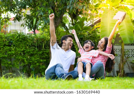 A happy young family spends time playing together in the garden at the front of house the vacation.