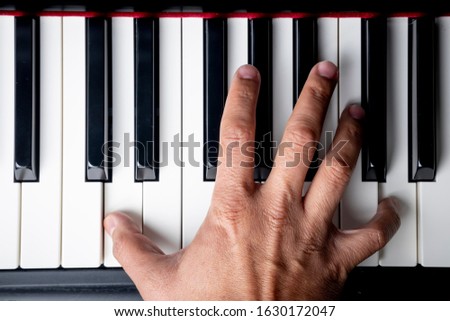 right hand playing a D octave chord on the piano Royalty-Free Stock Photo #1630172047