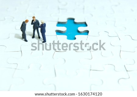 Business strategy conceptual photo - three miniature businessman discussion above missing puzzle jigsaw