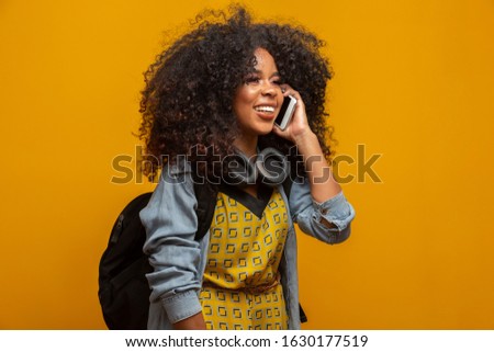 Cute girl talking on the phone. Communicating on the phone in yellow background.