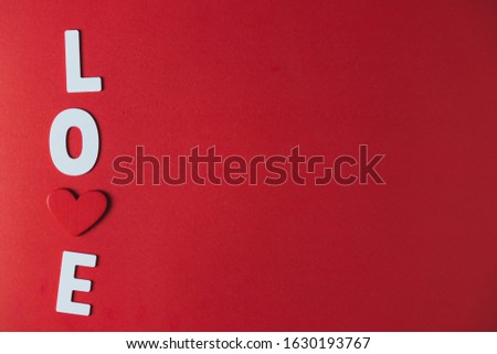 White wooden letters and red wooden hearts on a red background