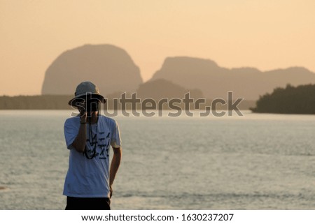 male asian take a photo and beautiful sea in the early morning background