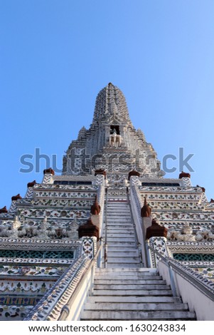 White pagoda in Wat Arun temple and blue sky. Ancient statues around base of pagoda. Wat Arun is a ancient monument in Thailand.