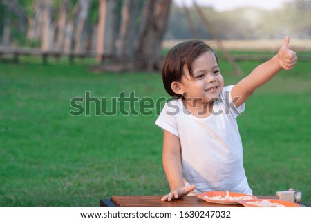 Happy little boy playing at park, showing thumb up
