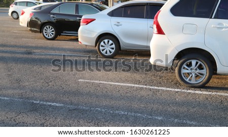 Closeup of rear, back side of white car with  other cars parking in outdoor parking area in bright sunny evening.