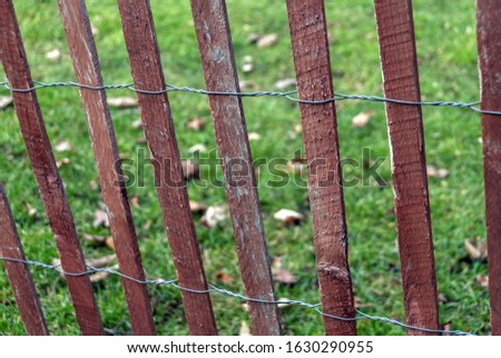 A closeup shot of a fence made with several brown pieces of wood and metal strings