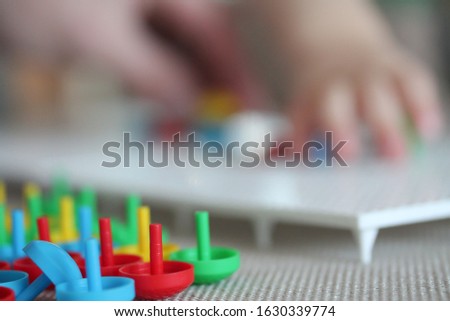 Child playing with mushroom nail mosaic. Blurred copyspace background. Father and baby playing together concept. Educational toy DIY puzzle. Colorful jigsaw pegboard. Hobby and leisure time