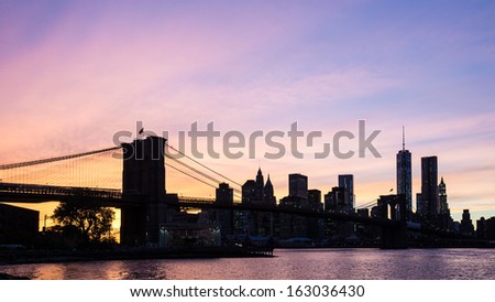 New York City Brooklyn Bridge with downtown skyline over East River during sunset